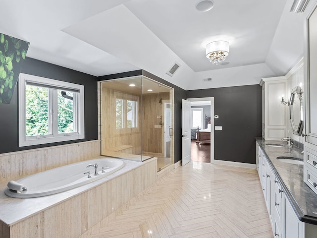 ensuite bathroom with plenty of natural light, a garden tub, a sink, and a shower stall