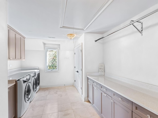 clothes washing area with light tile patterned flooring, baseboards, independent washer and dryer, cabinet space, and attic access