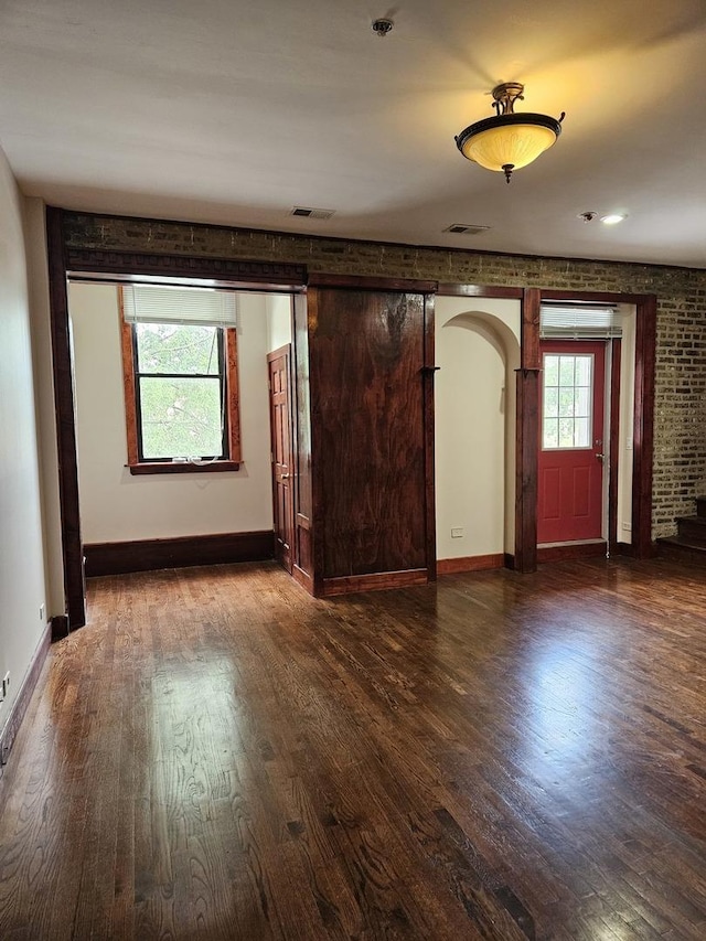 entryway with dark wood-type flooring and brick wall