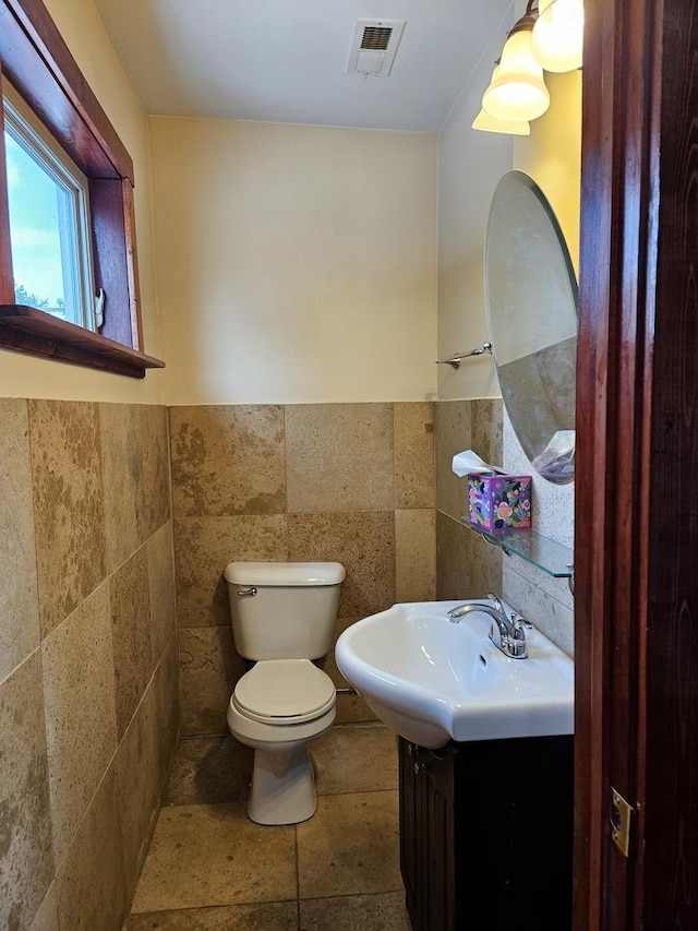 bathroom with vanity, toilet, and tile walls