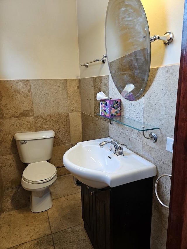 bathroom with vanity, toilet, and tile walls