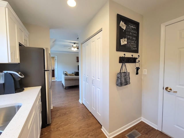 kitchen with stainless steel refrigerator, white cabinets, light stone counters, ceiling fan, and hardwood / wood-style flooring