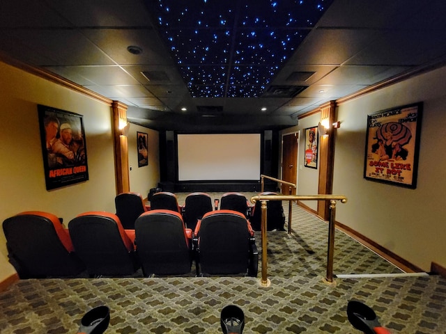 carpeted cinema room featuring ornamental molding and a drop ceiling