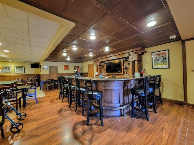 bar with a paneled ceiling and hardwood / wood-style flooring