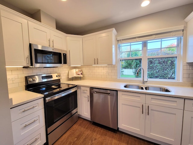 kitchen featuring white cabinetry, stainless steel appliances, dark hardwood / wood-style flooring, decorative backsplash, and sink