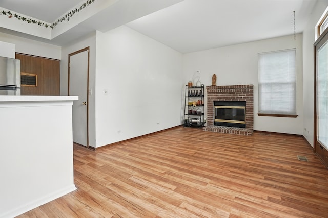1406 Trescott St, Mundelein, IL 60060 - unfurnished living room with light wood finished floors, a brick fireplace, and baseboards