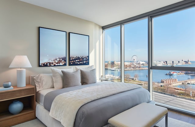 bedroom featuring a water view, hardwood / wood-style flooring, and a wall of windows