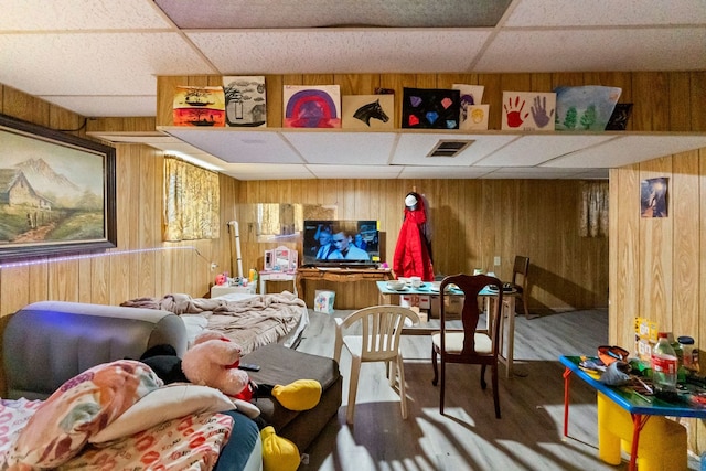 game room featuring wood walls, hardwood / wood-style floors, and a paneled ceiling