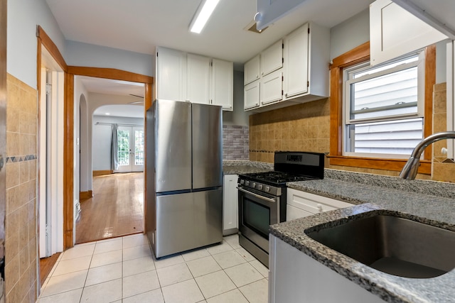 kitchen featuring dark stone counters, light tile patterned floors, sink, appliances with stainless steel finishes, and white cabinetry