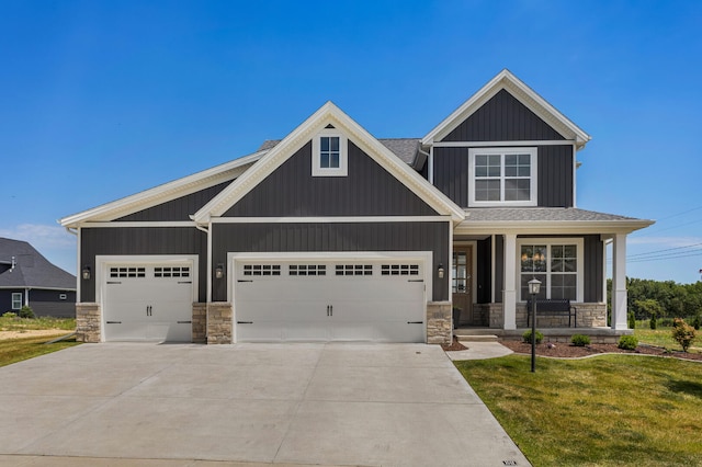 craftsman house with a front yard, a garage, and covered porch