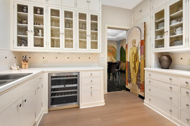 bar featuring white cabinetry, decorative backsplash, light hardwood / wood-style flooring, and beverage cooler