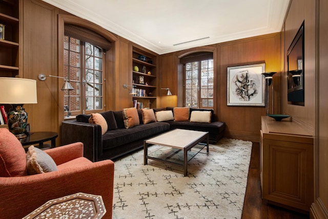 living area with plenty of natural light, built in features, and wood walls