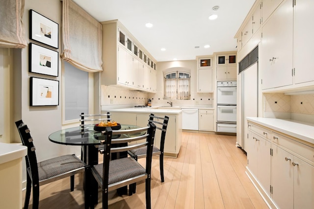 kitchen featuring white appliances, decorative backsplash, and light wood-type flooring