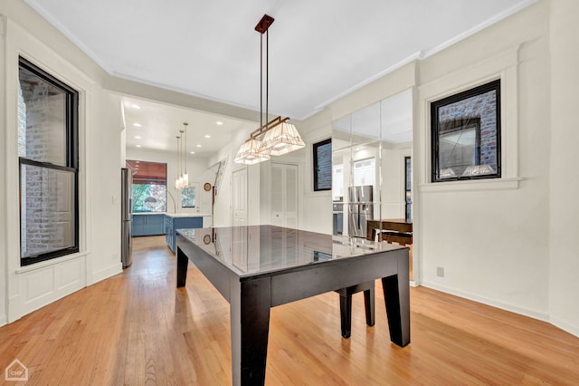 game room with crown molding, a chandelier, and light hardwood / wood-style flooring