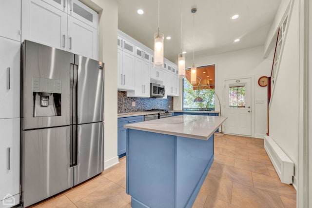 kitchen featuring backsplash, a kitchen island, blue cabinets, appliances with stainless steel finishes, and decorative light fixtures