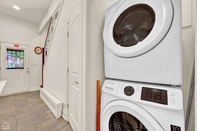 laundry area featuring stacked washer / drying machine and light tile patterned floors