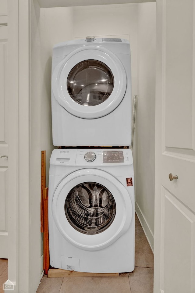 laundry room featuring light tile patterned flooring and stacked washer / dryer