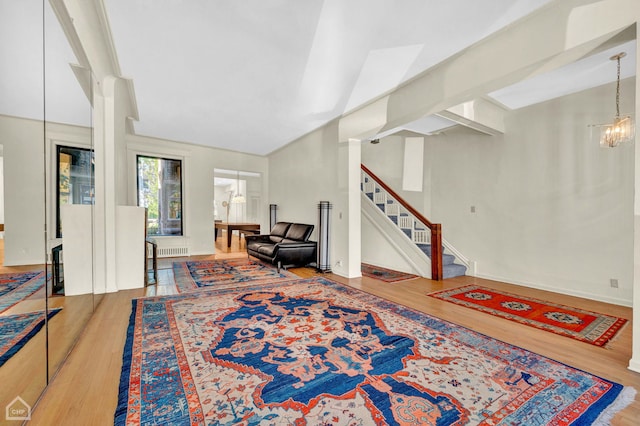 living room with lofted ceiling with beams, hardwood / wood-style floors, and a chandelier