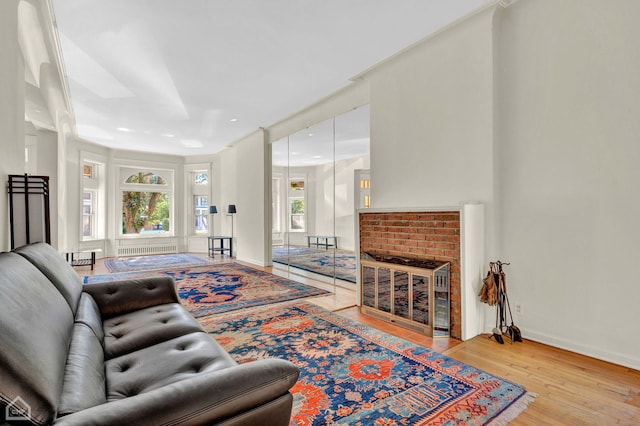 living room featuring a brick fireplace and light wood-type flooring