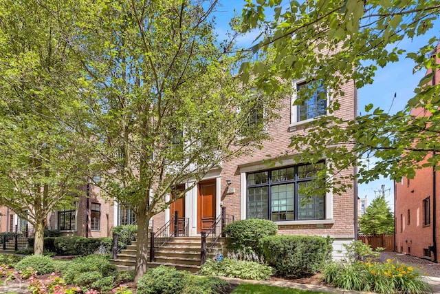 view of front of home featuring fence and brick siding