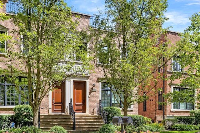 view of property hidden behind natural elements with brick siding