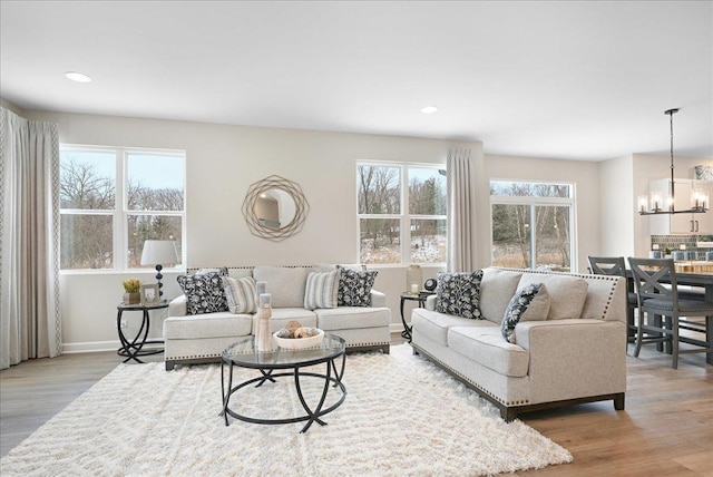 living room featuring a chandelier, wood finished floors, and a healthy amount of sunlight