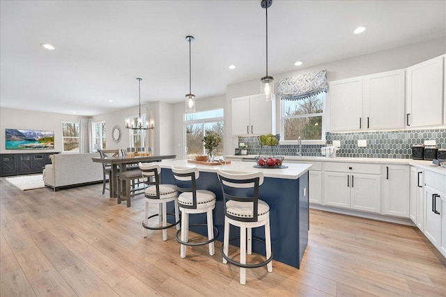 kitchen with a center island, white cabinets, light countertops, and hanging light fixtures