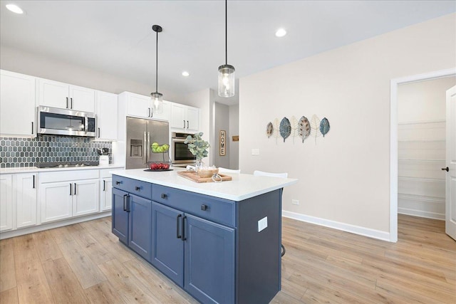 kitchen with white cabinets, decorative light fixtures, blue cabinets, stainless steel appliances, and light countertops