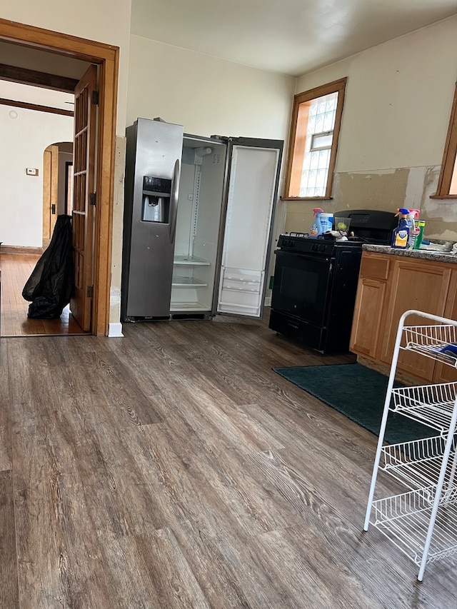 kitchen featuring hardwood / wood-style flooring, black range oven, and stainless steel refrigerator with ice dispenser