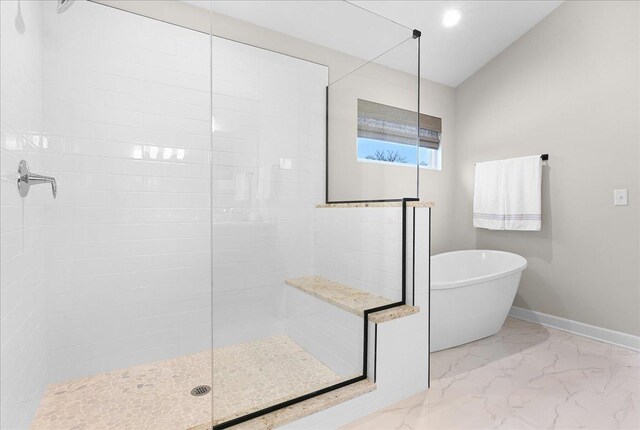 full bath featuring a freestanding bath, marble finish floor, a tile shower, and baseboards