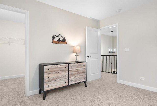 interior space with a chandelier, carpet, a walk in closet, and baseboards