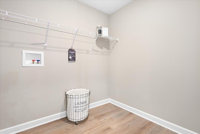 clothes washing area featuring laundry area, washer hookup, wood finished floors, and baseboards