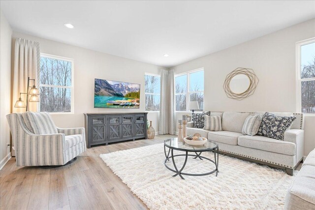 living room with a wealth of natural light, light wood-type flooring, and recessed lighting