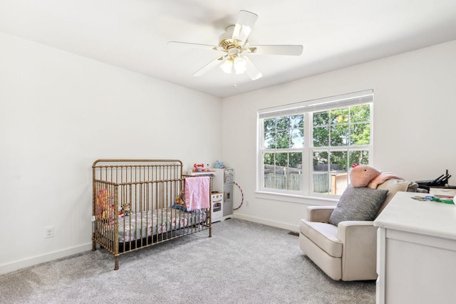 carpeted bedroom featuring ceiling fan and a crib