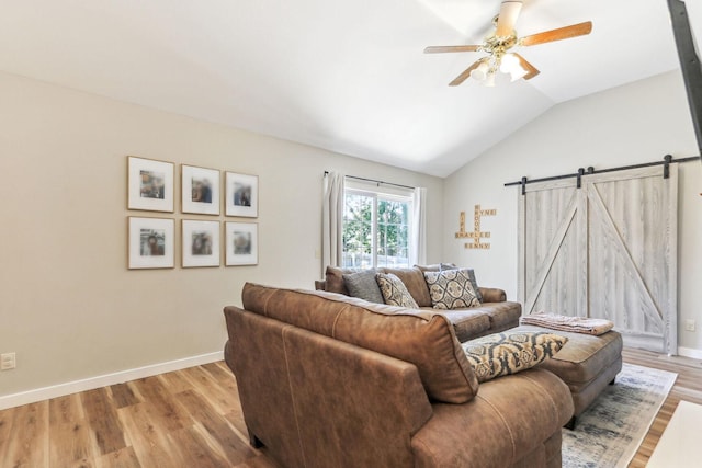 living room featuring ceiling fan, a barn door, light hardwood / wood-style floors, and lofted ceiling