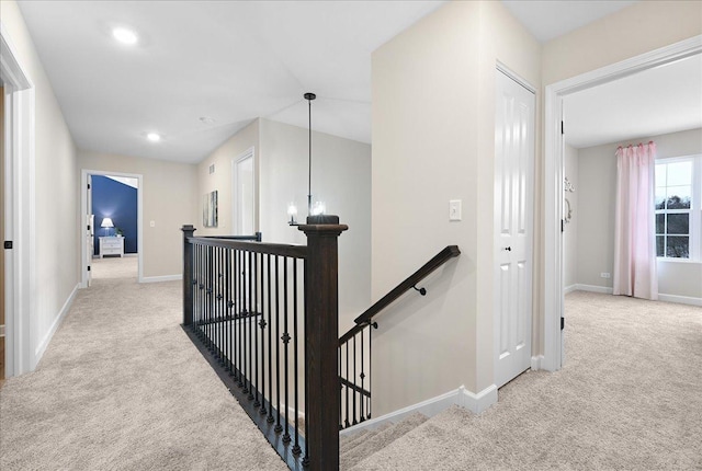 hall featuring an upstairs landing, recessed lighting, baseboards, and light colored carpet