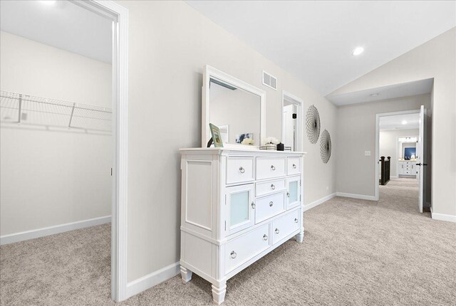 hallway featuring light colored carpet and vaulted ceiling