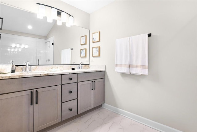 bathroom with marble finish floor, double vanity, a sink, a shower stall, and baseboards