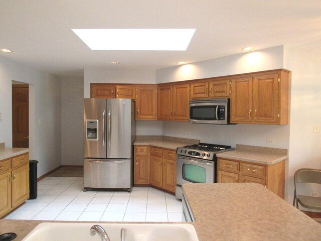 kitchen featuring stainless steel appliances, a skylight, and light tile patterned floors