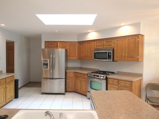 kitchen with light tile patterned floors, a skylight, and appliances with stainless steel finishes