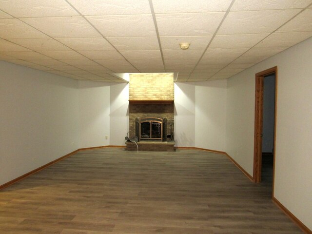 unfurnished living room featuring a fireplace, a drop ceiling, and hardwood / wood-style floors