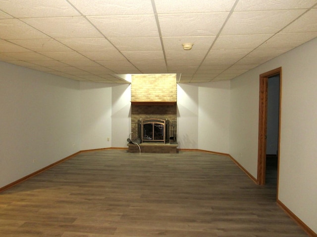 basement featuring a drop ceiling, hardwood / wood-style flooring, and a large fireplace