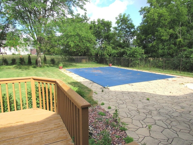 view of pool with a deck, a patio area, and a lawn