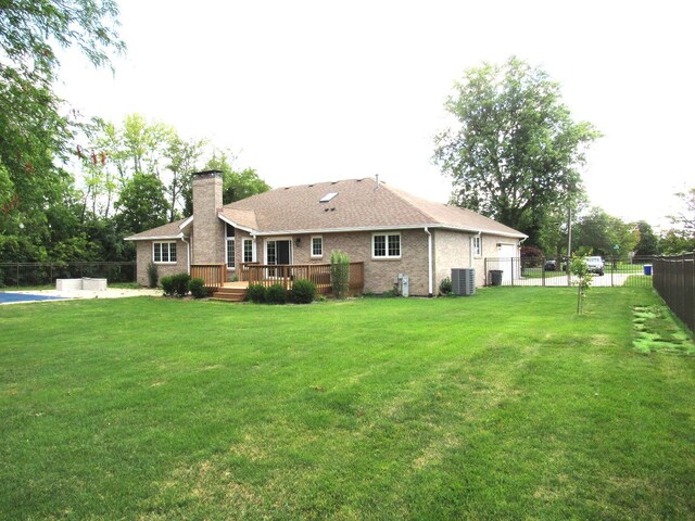 rear view of house featuring a deck, central air condition unit, and a lawn