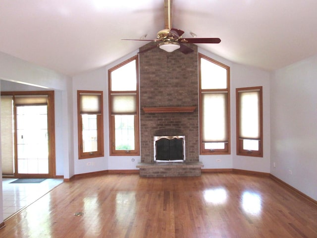 unfurnished living room with lofted ceiling, a brick fireplace, ceiling fan, and light wood-type flooring