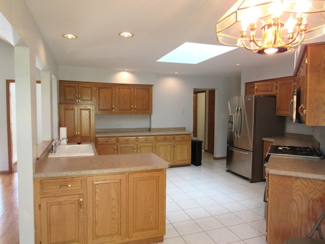 kitchen with a notable chandelier, light tile patterned flooring, stainless steel appliances, a skylight, and sink