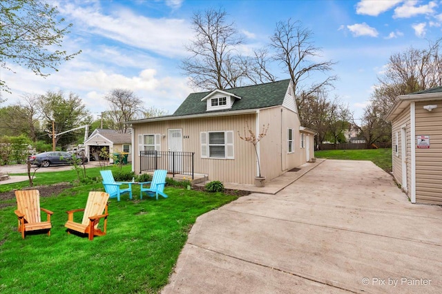 view of front of house featuring an outdoor fire pit, driveway, a front yard, and roof with shingles