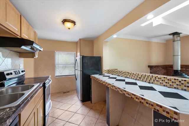 kitchen featuring light brown cabinetry, decorative backsplash, stainless steel appliances, and light tile patterned floors