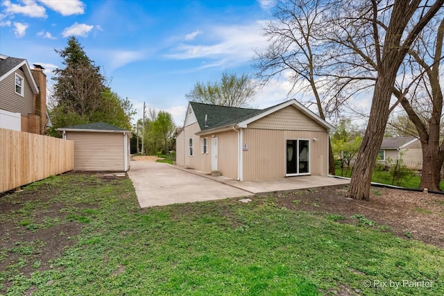 back of house featuring a patio area, an outbuilding, and a lawn