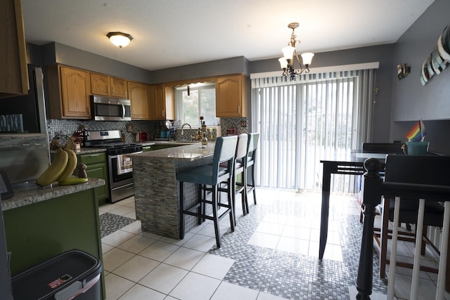 kitchen with stainless steel appliances, a kitchen breakfast bar, a chandelier, pendant lighting, and light tile patterned flooring